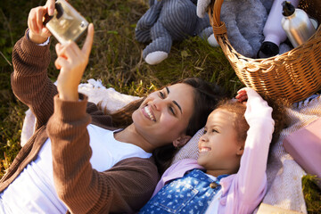 Obraz premium Selfie time. High angle shot of an attractive young woman and her daughter taking selfies during their picnic in the park.