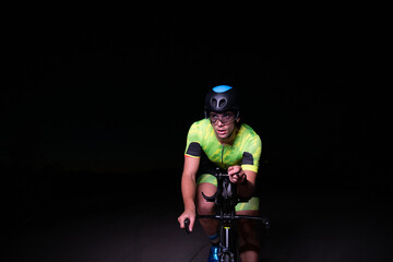 Fototapeta na wymiar A triathlete rides his bike in the darkness of night, pushing himself to prepare for a marathon. The contrast between the darkness and the light of his bike creates a sense of drama and highlights the