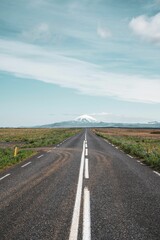 Vertical shot of a  scenic, empty roadway leads to the Hekla mountain range on a partly cloudy day