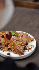Delicious french toast with fresh fruits and maple sirup. Tasty breakfast scene or dessert with toast, strawberries, blueberries and powdered sugar.
