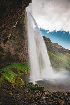 Majestic Seljalandsfoss waterfall cascades down behind a rocky outcrop in Iceland. © Fyod Sap/Wirestock Creators