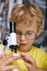 Close-up of a cute little kid wearing glasses and a yellow T-shirt emitting a substance using a...