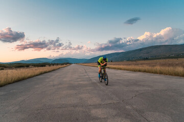  Triathlete riding his bicycle during sunset, preparing for a marathon. The warm colors of the sky...