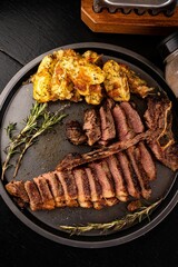 Top view of a meal of sizzling steaks on a plate, accompanied by cubed potatoes cooked with herbs