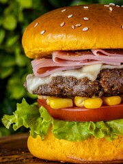 Delicious cheeseburger served with freshly-sliced tomatoes and corn on the cob, on a tabletop