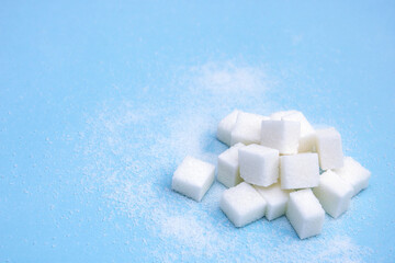 white sugar in cubes on a blue background with copy space, culinary background