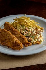 Platter of fish fingers and coleslaw salad, served on a white plate, ready to be enjoyed