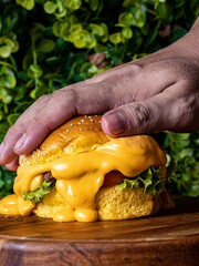 Person's hand reaching out to grab a juicy cheeseburger dripping with delicious sauce