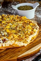 Freshly made pizza with assorted toppings and cheese on a wooden board