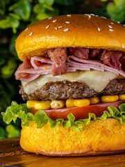 Delicious cheeseburger served with freshly-sliced tomatoes and corn on the cob, on a tabletop