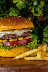 Delicious cheeseburger served with freshly-sliced tomatoes and corn on the cob, on a tabletop