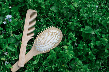 Wooden hairbrushes on green nature leaves background, natural hair care products