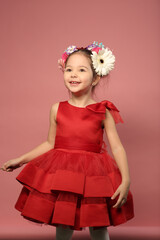 little girl in red dress with flowers in hair dress happy closeup portrait on pink background