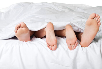 Woman's and man's feet in bed under a blanket