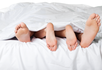 Woman's and man's feet in bed under a blanket
