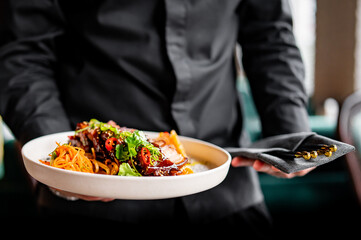 chef hand hold plate whith Stewed pork slice with noodles and vegetables