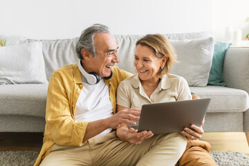Senior couple resting at home, shopping online with laptop, ordering food or preparing for vacation