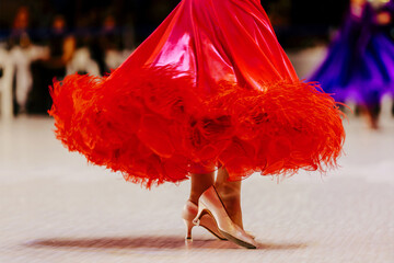 close-up red ball gown and feet in slipper of female dancer on parquet