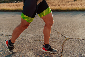 Fototapeta na wymiar Closeup of muscular legs of a triathlete in professional equipment running early in the morning, preparing for a marathon, dedication to sports and readiness for marathon challenges