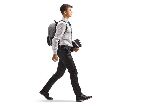 Male student with a backpack in a shirt and tie holding books and walking