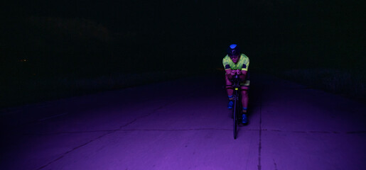 A triathlete rides his bike in the darkness of night, pushing himself to prepare for a marathon....