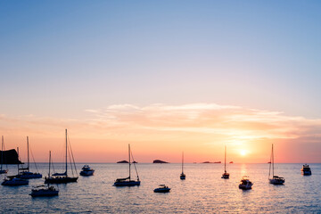  Several pleasure boats anchored in a cove on the island of Ibiza to watch the sunset.