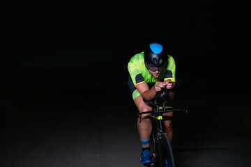 A triathlete rides his bike in the darkness of night, pushing himself to prepare for a marathon....
