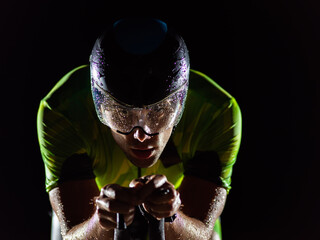 A triathlete rides his bike in the darkness of night, pushing himself to prepare for a marathon. The contrast between the darkness and the light of his bike creates a sense of drama and highlights the