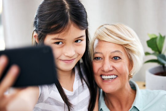 My phone is full of pictures just like this. a little girl taking a selfie at home with her grandmother.