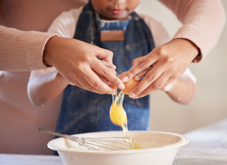 Baking together builds fond family memories. Closeup shot of a little girl helping her mother crack an egg while baking together at home.