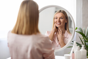 Self-Care Concept. Attractive Middle Aged Female Looking At Mirror At Home