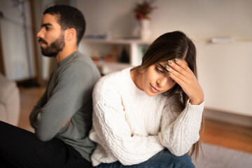 Fototapeta premium Despaired sad offended young arab husband ignores european wife back to back after quarreling