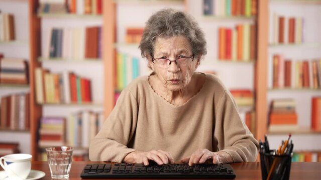Funny point of view POV of the computer screen portrait of angry frustrated elderly old senior woman with hammer contemplating breaking laptop and is frustrated with taxes paying bills, bad news.
