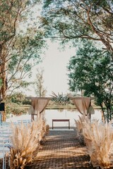 Organized row of white chairs on a walkway decorated with flowers leading to the wedding altar