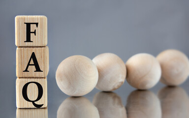 FAQ - acronym on wooden cubes on the background of light balls.
