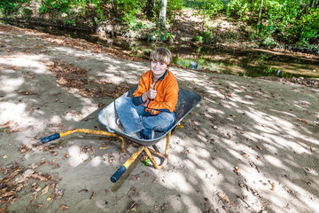 child sits in the wheel barrow and relaxes