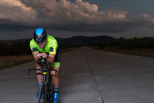 A triathlete rides his bike in the darkness of night, pushing himself to prepare for a marathon. The contrast between the darkness and the light of his bike creates a sense of drama and highlights the © .shock