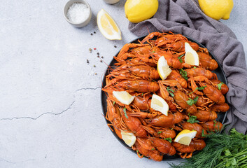 top view of cooked crawfish platter with lemons and spices on cement background