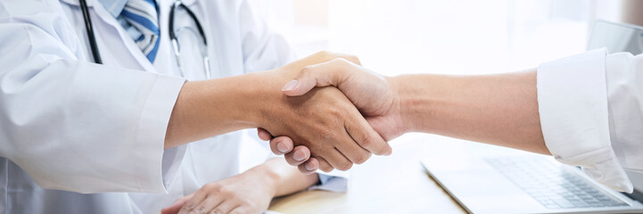 Male doctor in white coat shaking hands with the patient after s