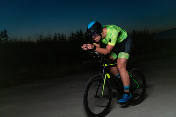 A triathlete rides his bike in the darkness of night, pushing himself to prepare for a marathon....