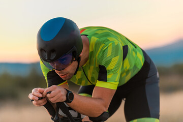  Close up photo of triathlete riding his bicycle during sunset, preparing for a marathon. The warm...