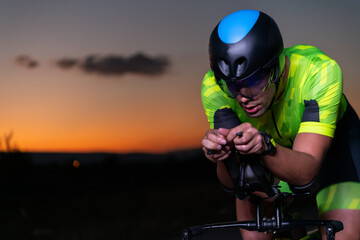 A triathlete rides his bike in the darkness of night, pushing himself to prepare for a marathon....