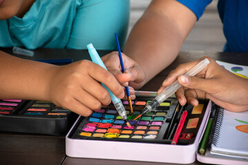 Closeup watercolor cases and hands of asian boys which spending their free times by drawing,...