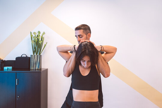 Confident osteopath healing head of client in clinic