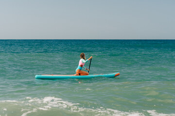 Woman swimming on sup board in sea.