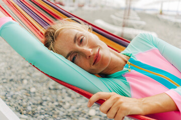 Fototapeta na wymiar Happy smiling carefree young woman relaxing in a hammock on the beach.