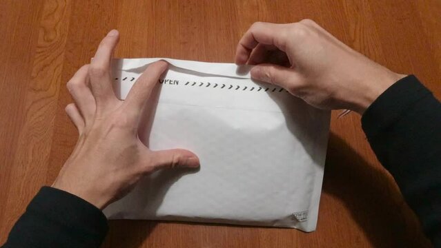 家で届いた封筒を開ける手元の映像