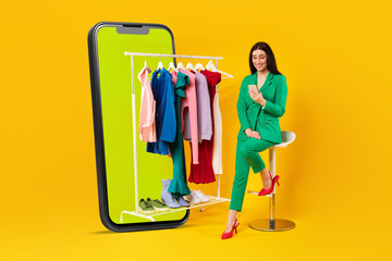 Mobile shopping. Happy female choosing clothes on rail in smartphone, sitting on chair and using phone
