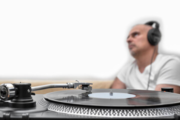 Vinyl record player against the background of a blurred man in headphones.