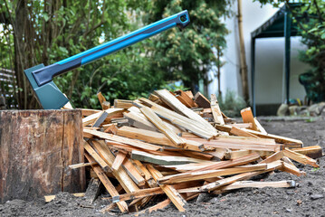 Axe on a log for chopping firewood and a pile of chopped firewood